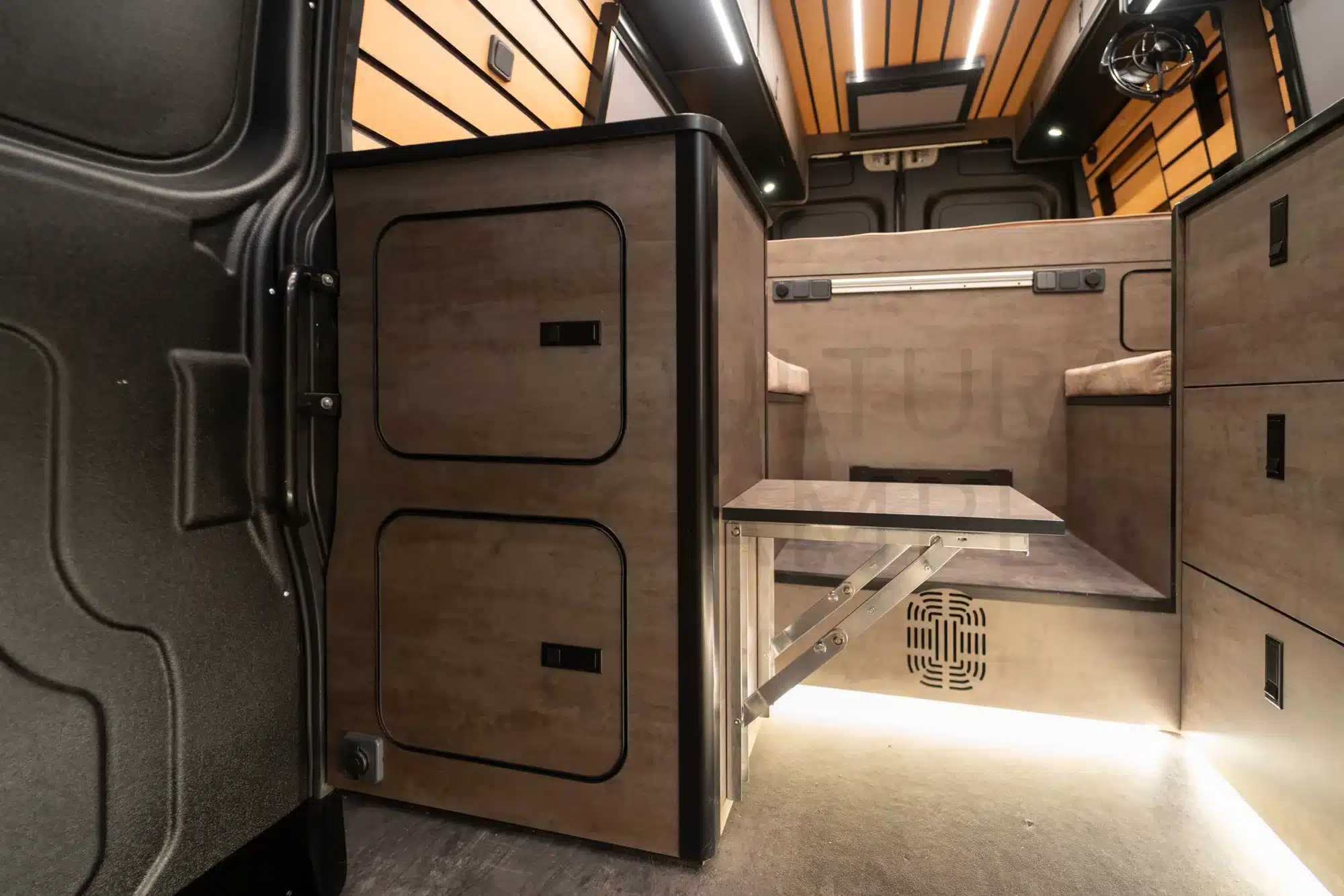 Moderner Innenraum eines Iveco Daily 4x4 L3H2 Campers mit klappbarem Tisch und viel Stauraum