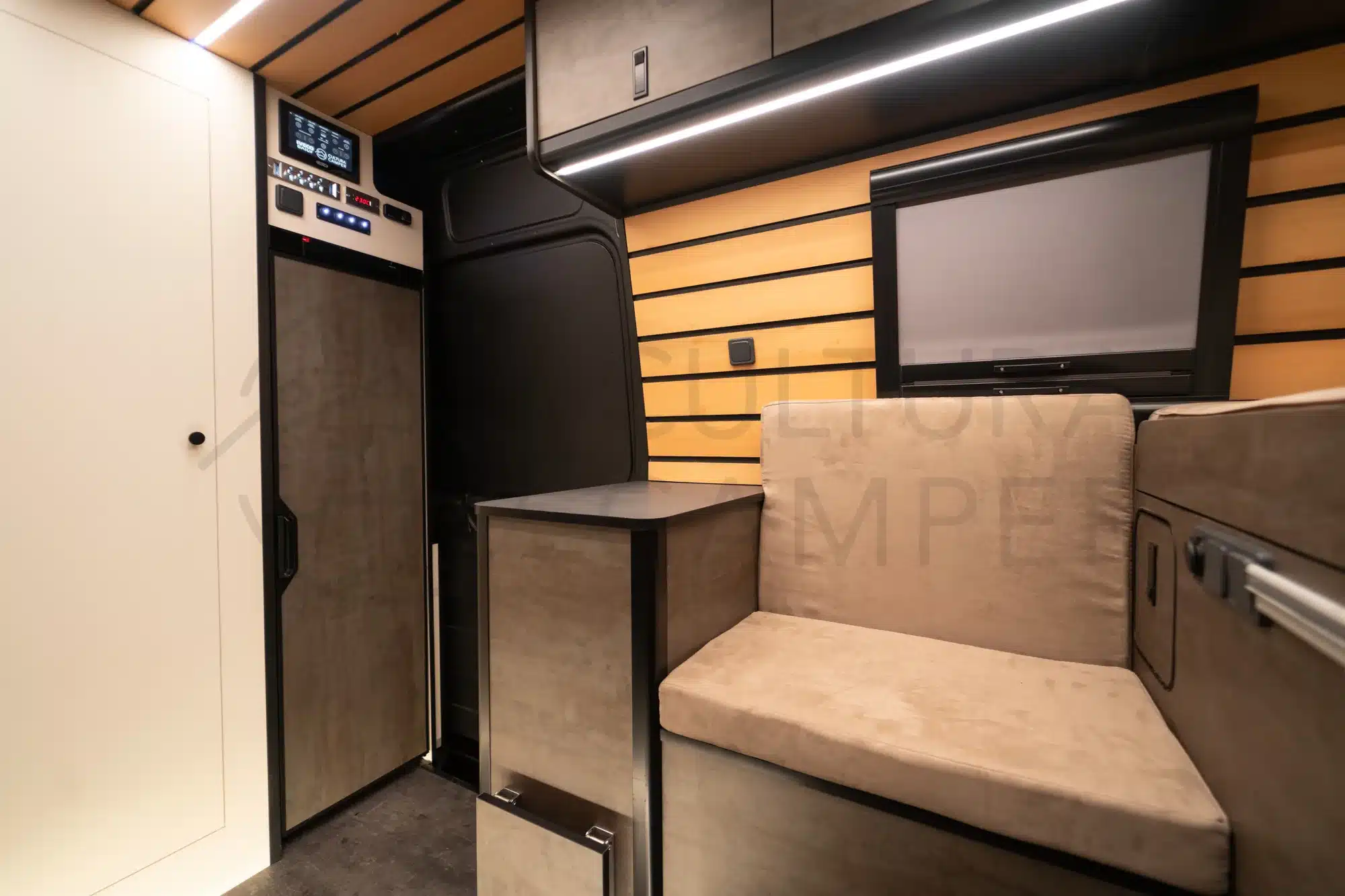 Hochwertig ausgebauter Innenraum eines Iveco Daily 4x4 L3H2 Campers, mit Sitzbank, Steuerungspanel, Küchenmodul und Fenster mit Jalousie.