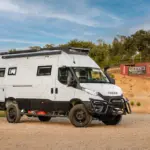 Seitlich aufgenommener Iveco Daily 4x4 L4H3 Expeditionscamper auf unbefestigtem Gelände mit Offroad- und Campingausstattung.