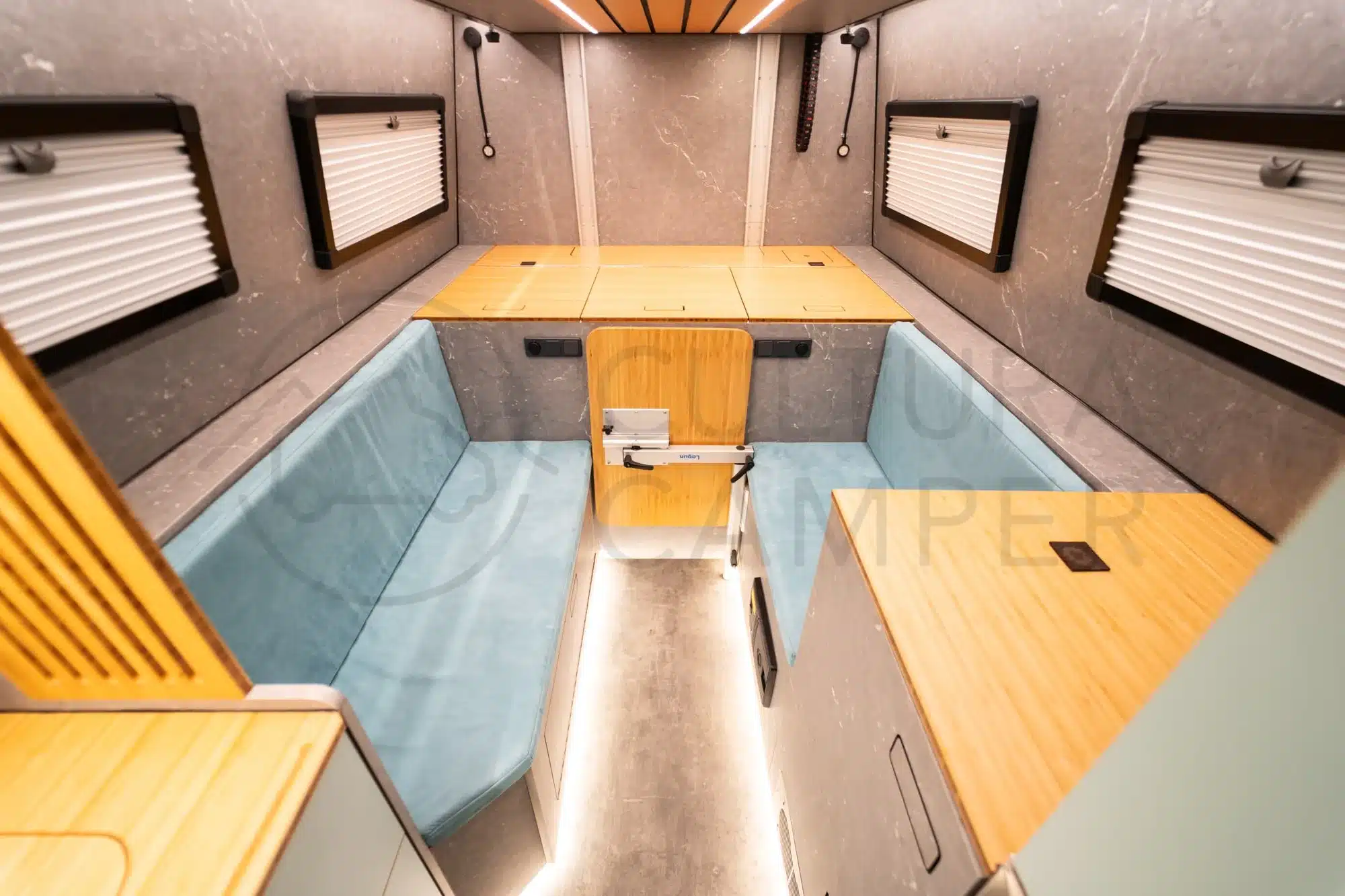 Innenraum eines zum Expeditionsmobil ausgebauten Iveco Daily 4x4 L4H3 mit Sitzbänken, Klapptisch und viel Stauraum.