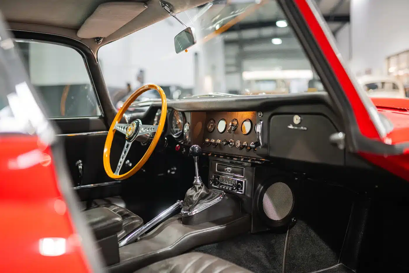 Innenansicht eines restaurierten Jaguar E-Type Serie 1 4.2 Roadster von 1965 mit klassischem Armaturenbrett, Schaltgetriebe und braunem Lederinterieur.