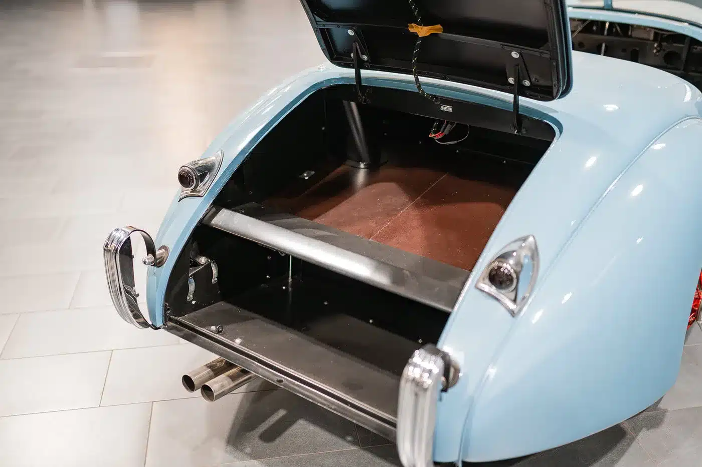 Der geöffnete Kofferraum einer blauen Jaguar Karosserie mit sichtbaren Rückleuchten und Auspuffrohren