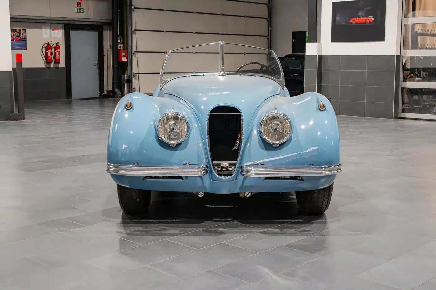 Blaue Jaguar Karosserie von vorne in einer Halle, klassische Linien und große Rundscheinwerfer.