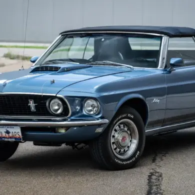 Ford Mustang 428 Cobra Jet Convertible von 1969 in blau, Cabrio mit geschlossenem Verdeck, Front- und Seitenansicht, auf einem Parkplatz.