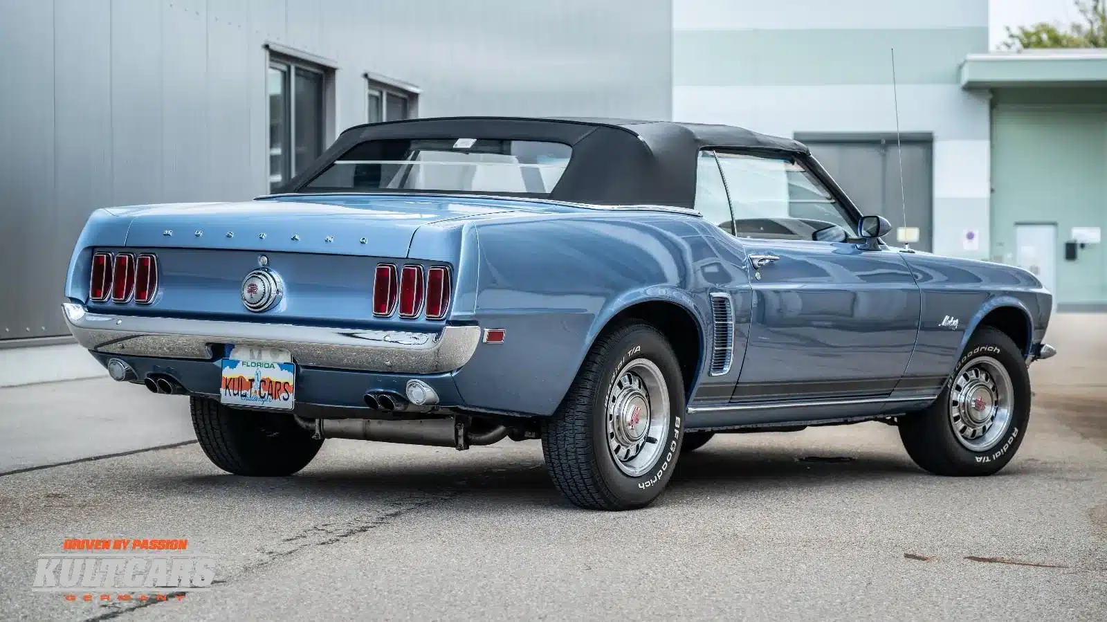 Ford Mustang 428 Cobra Jet Convertible, Baujahr 1969, in blau mit schwarzem Verdeck, Heckansicht auf dem Hof von KULT CARS.