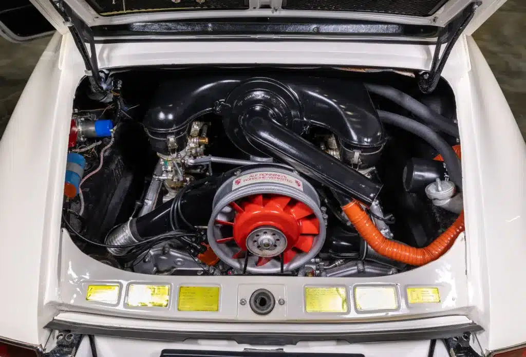 Geöffneter Motorraum eines klassischen Porsche-Sportwagens mit sichtbarem Boxermotor und originalen Details