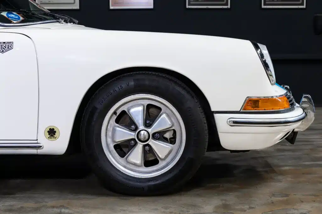 Detailaufnahme des Vorderkotflügels, Rads und Scheinwerfers eines weißen klassischen Sportwagens.