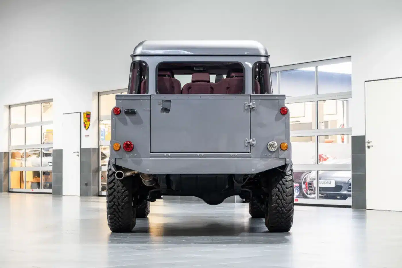 Heckansicht eines Land Rover Defender 110 Double Cab von 2011 in Stornoway Grau mit Aluminium-Heckdeckel, aufgenommen in einer Werkstatt.