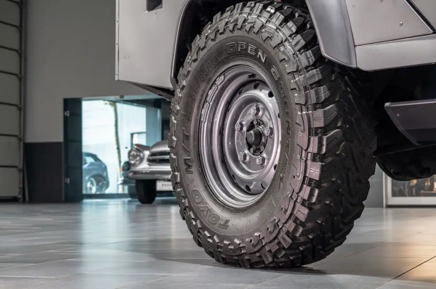 Grobstolliger Reifen am Land Rover Defender 110 Double Cab, Detailaufnahme in einer Garage.