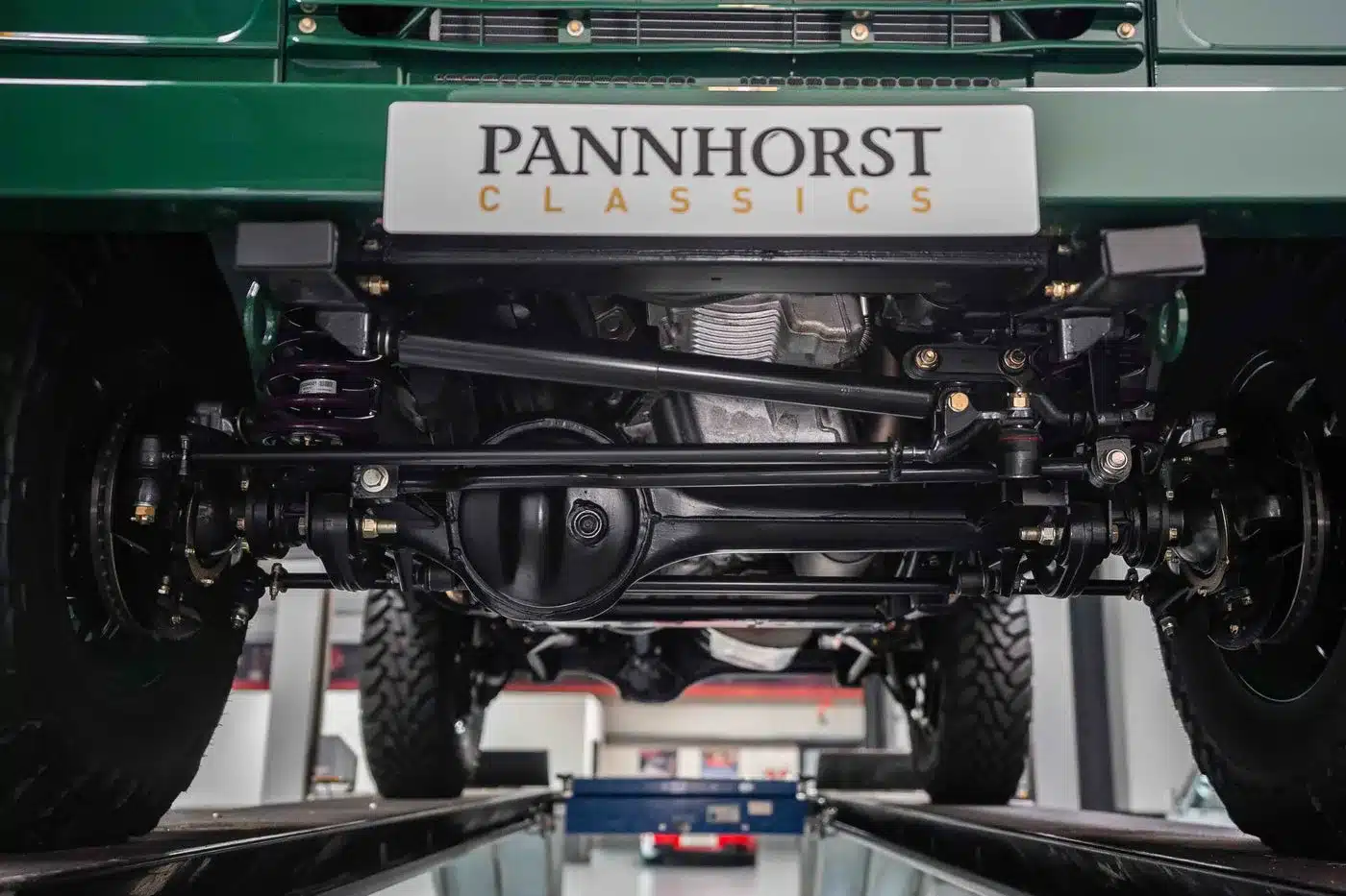 Nahaufnahme des restaurierten Unterbodens eines grünen Land Rover Defender 90 TD5 Cabriolet mit sichtbarem Fahrwerk und Achse