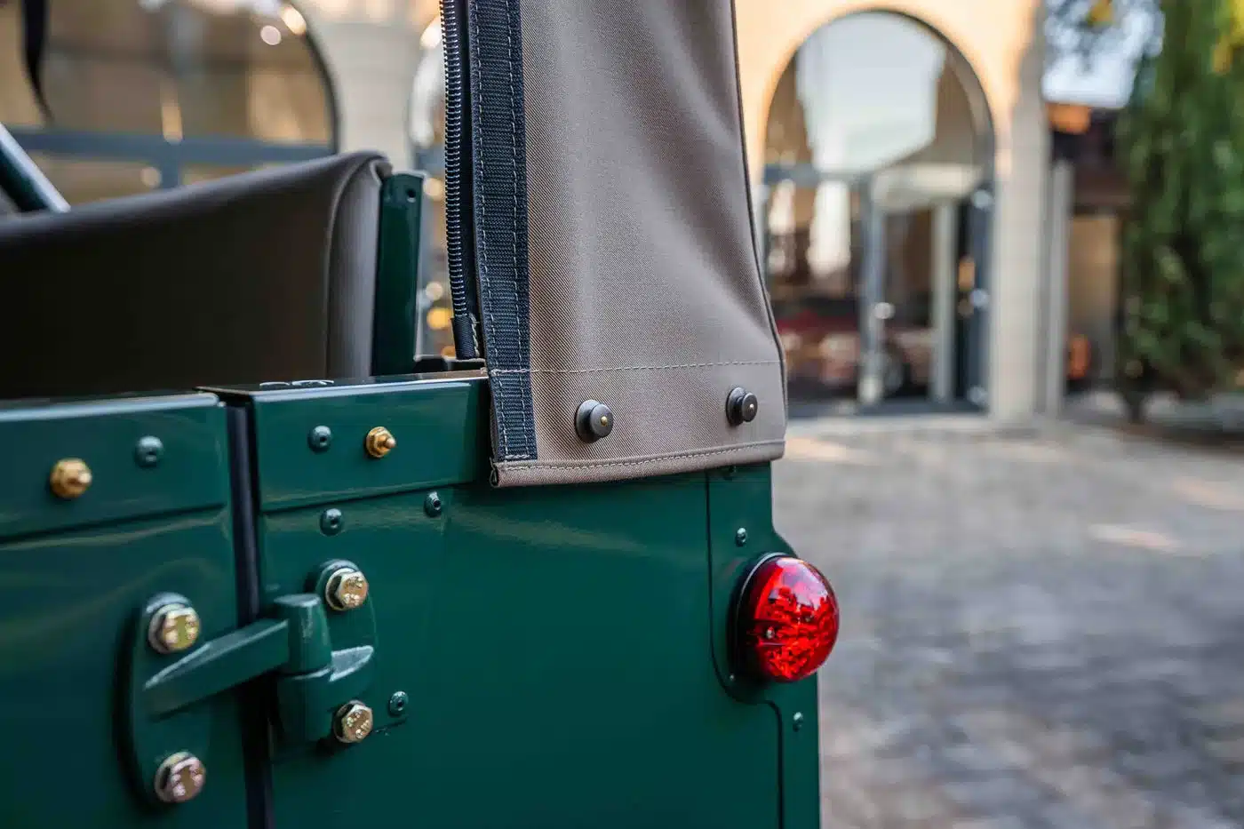 Detailaufnahme der cremefarbenen Cabrio-Plane und grünen Karosserie eines Land Rover Defender 90 TD5.