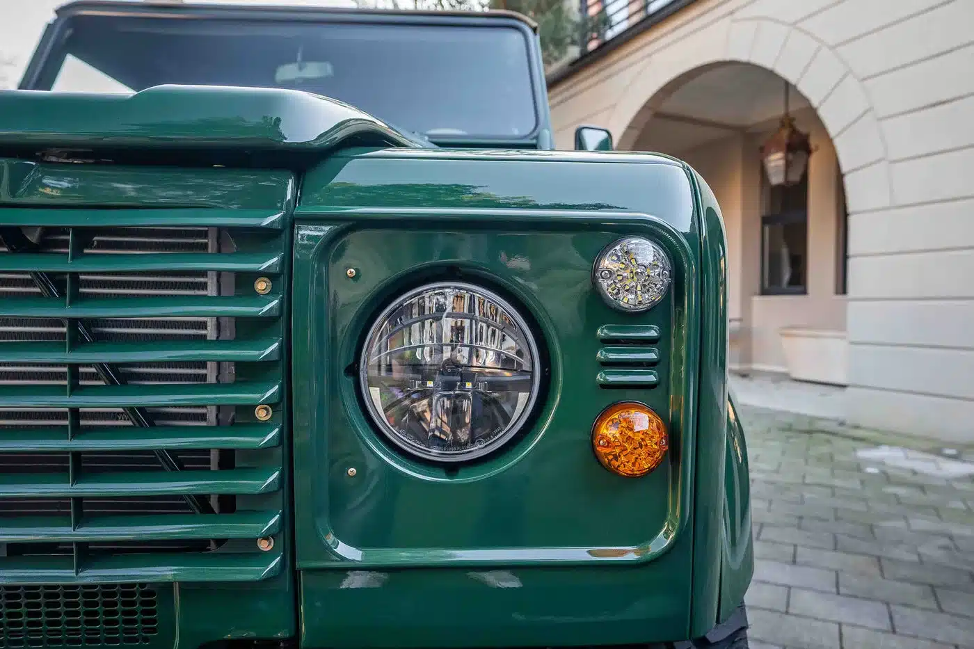Frontdetail des grünen Land Rover Defender 90 TD5 Cabriolets mit Scheinwerfer und Blinker
