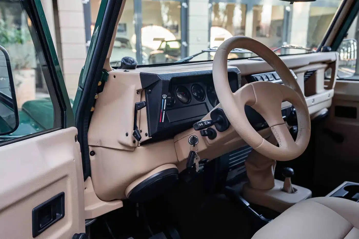 Innenansicht eines Land Rover Defender 90 TD5 Cabriolet mit beigem Kunstleder und schlichtem Armaturenbrett