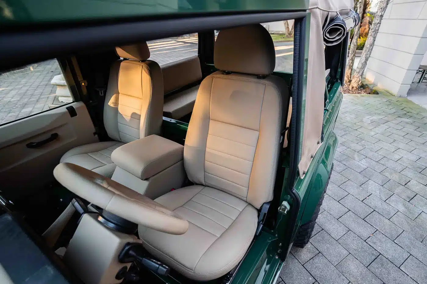 Innenraum eines Land Rover Defender 90 TD5 Cabriolets mit beigen Kunstledersitzen und cremefarbener Cabrio-Plane.