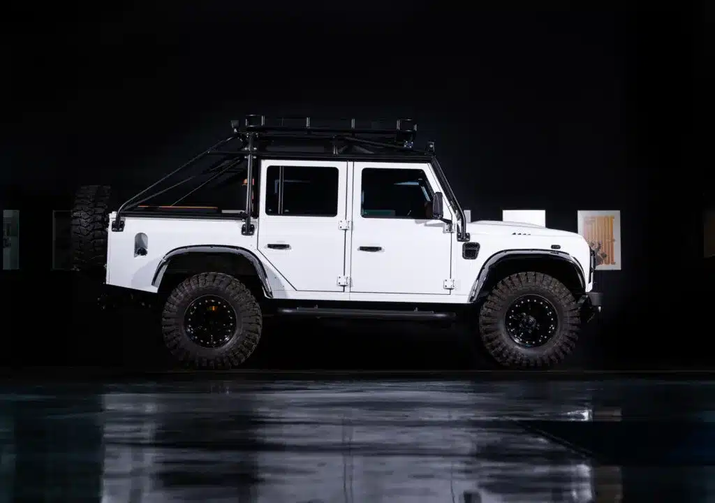 Weißer Land Rover Defender mit geländetauglicher Ausstattung auf dunklem Hintergrund