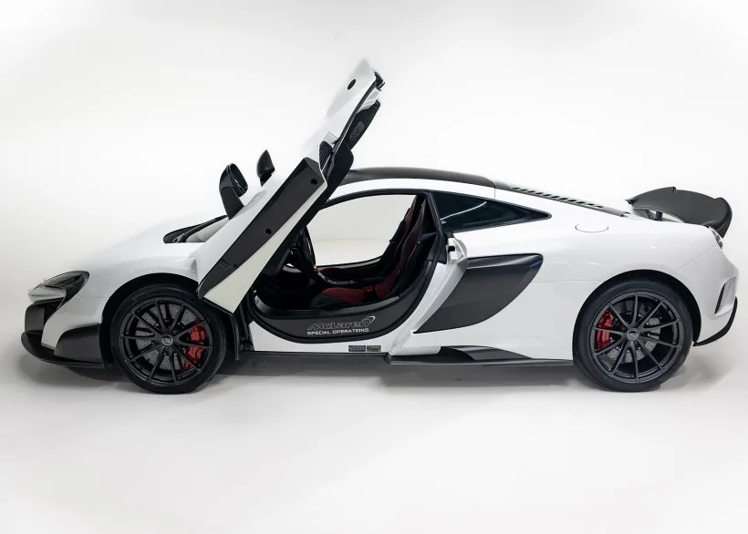Weißer McLaren 675LT mit geöffneter Fahrertür in einem Studio, klare Sicht auf das Interieur und die markanten Karosseriedetails.