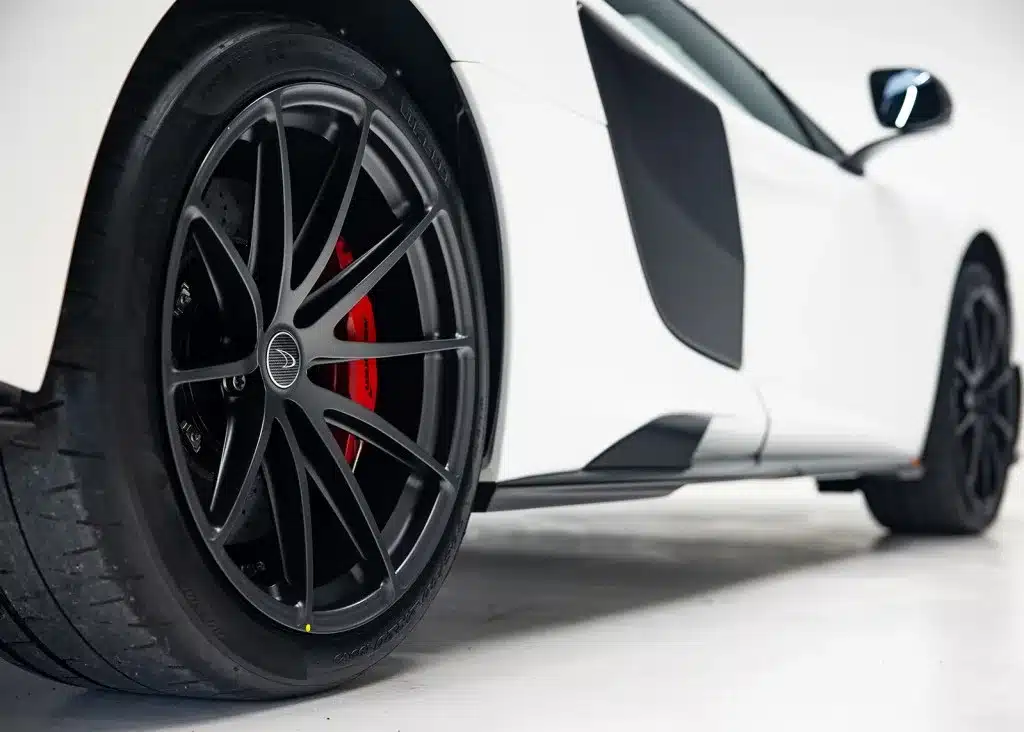 Nahaufnahme des vorderen Rads und Seitenschwellers eines weißen McLaren 675LT mit roten Bremssätteln