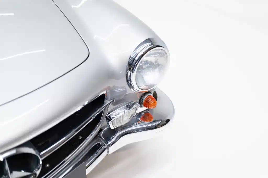 Nahaufnahme der silbernen Front mit Scheinwerfer und Blinker eines Mercedes 190 SL, Baujahr 1957.