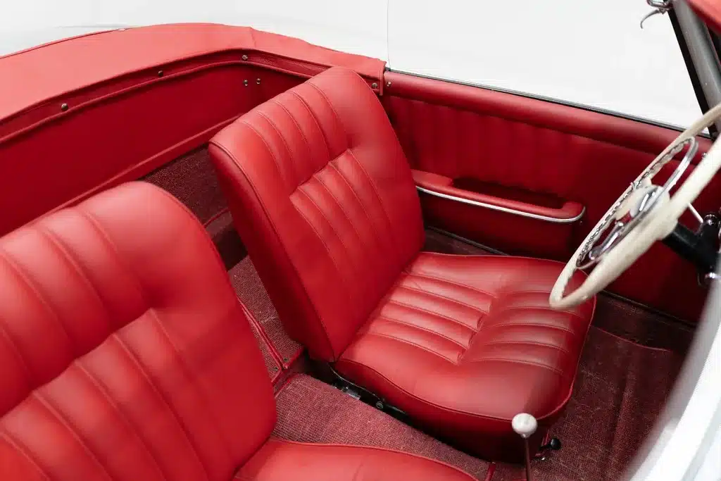 Innenraum des Mercedes 190 SL mit roten Ledersitzen und Lenkrad, restaurierter Zustand.