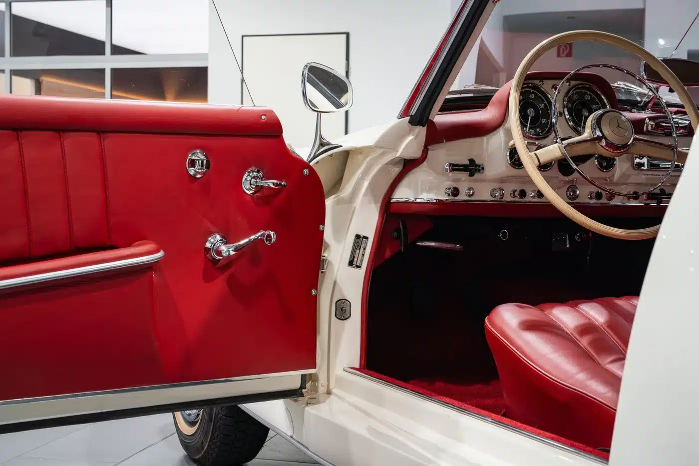 Geöffnete Fahrertür und detailreiches Armaturenbrett im roten Lederinterieur eines Mercedes-Benz 190 SL, Baujahr 1961