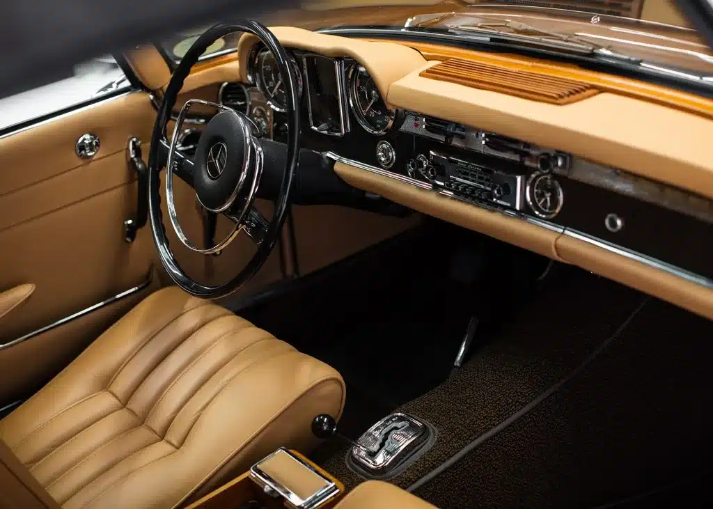 Innenraum einer Mercedes-Benz 230 SL Pagode mit beiger Lederausstattung, klassischem Lenkrad und Originalradio.
