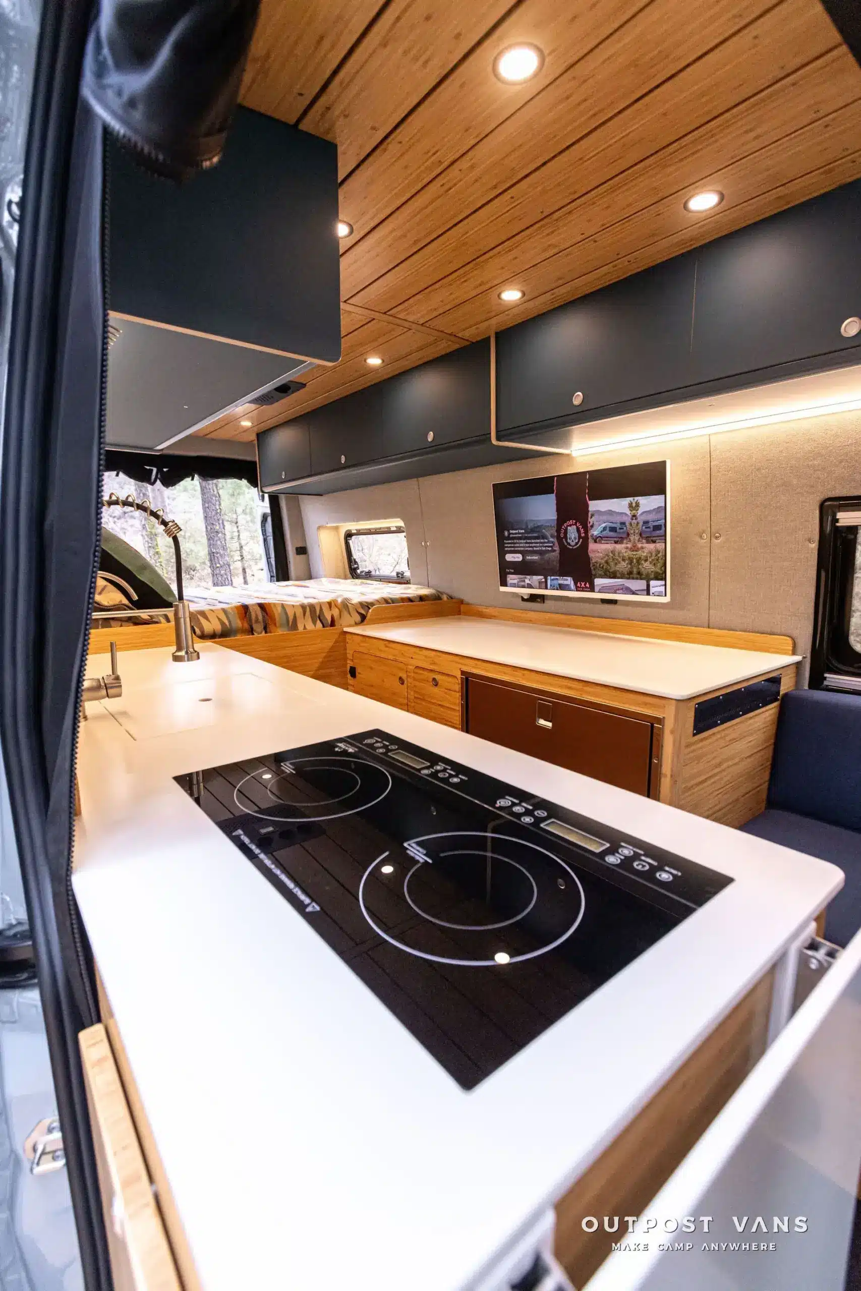 Innenraum eines ausgebauten Mercedes Sprinter 170 Güero mit hochwertiger Küchenzeile, Induktionskochfeld, Wohnbereich und Bambus-Lamellendecke