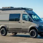 Mercedes-Benz Sprinter Lobo Campervan mit Dachträger, Außenkisten und Allrad, geparkt am Meer