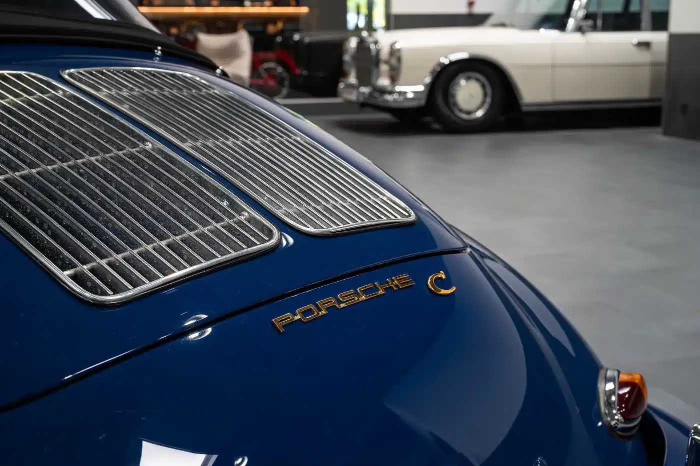 Detailansicht des blauen Porsche 356 C Cabriolet mit goldfarbenem Porsche C Schriftzug am Heck.