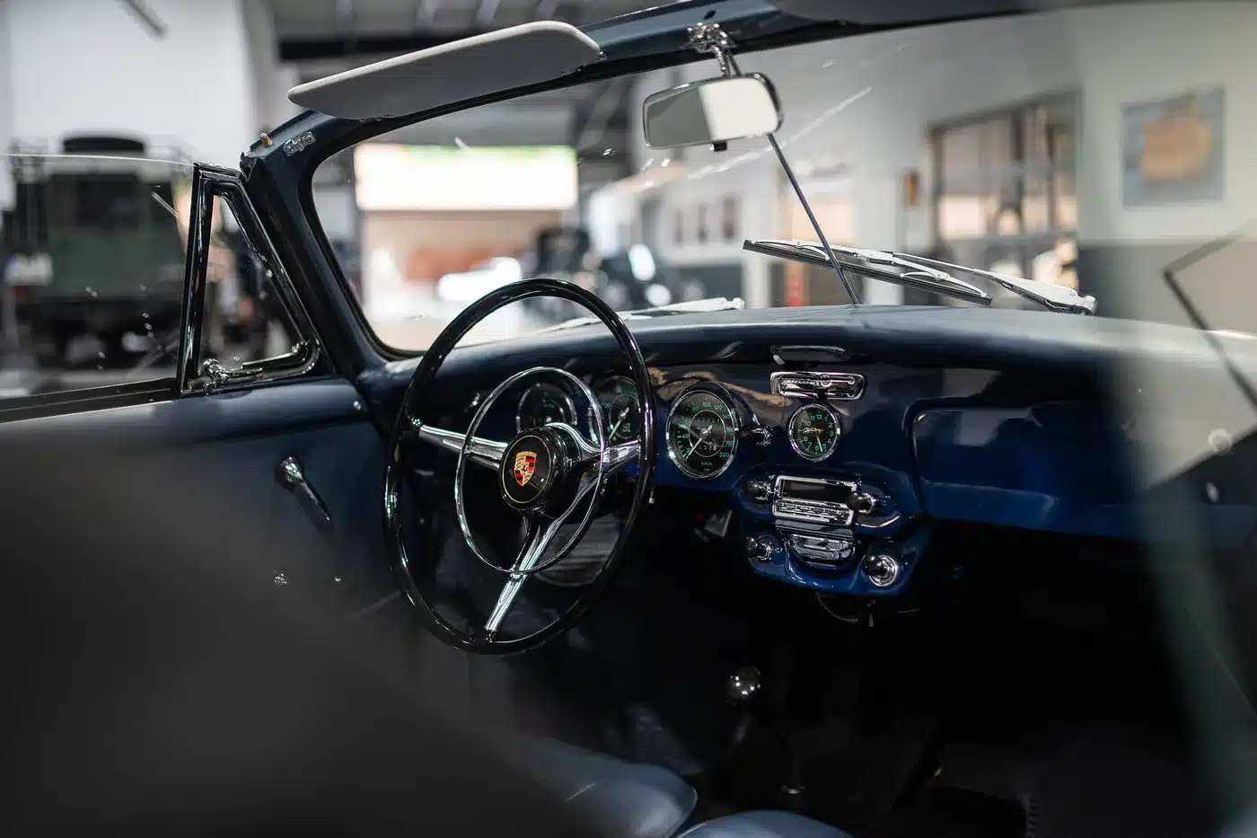 Blauer Innenraum und Armaturenbrett eines restaurierten Porsche 356 C Cabriolet, Blick durch die offene Tür.