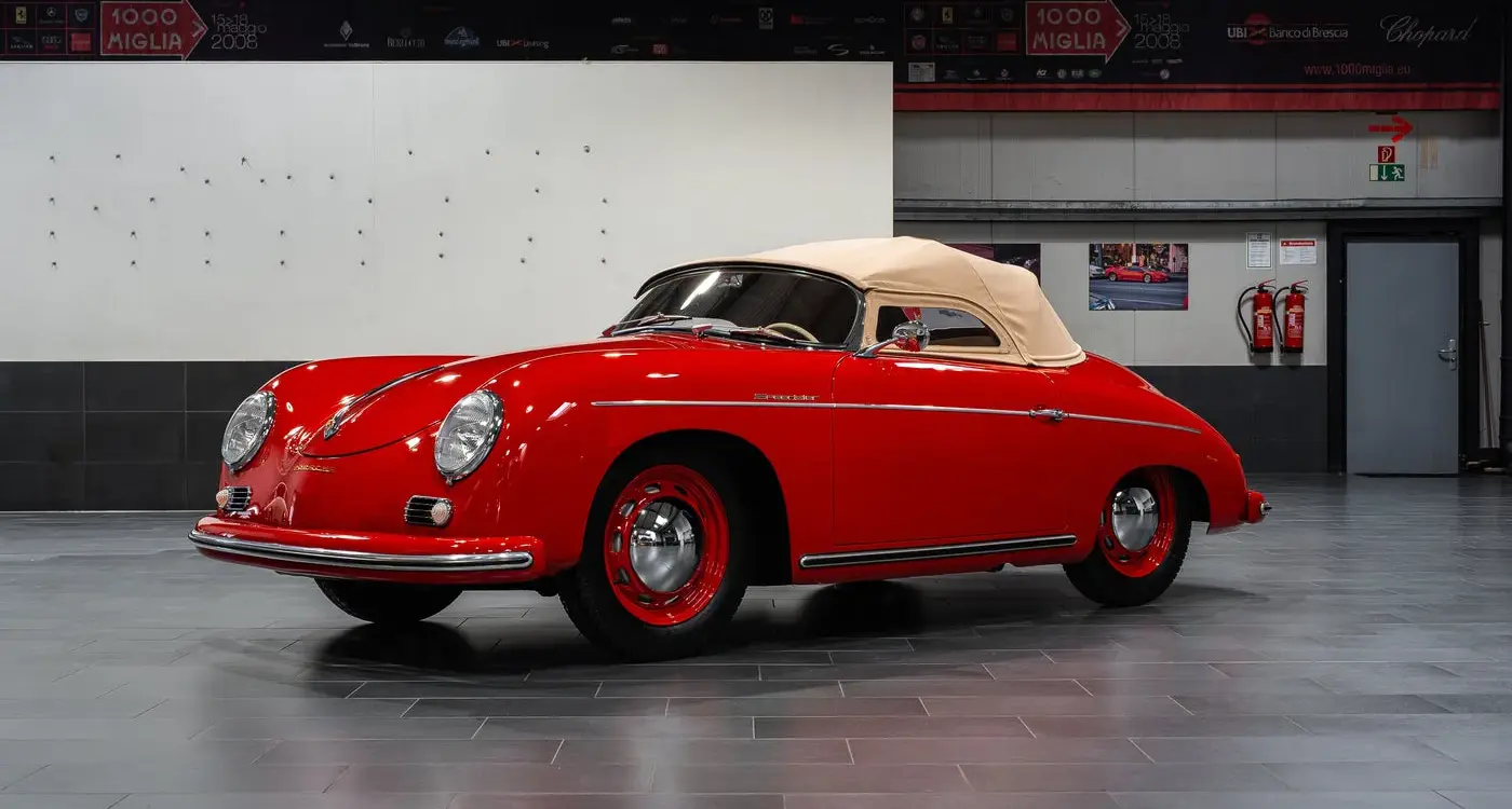 Restaurierter roter Porsche 356 Pre-A Speedster von 1955 mit beigem Verdeck in einer modernen Halle