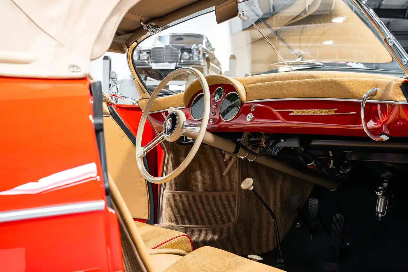 Innenraum eines Porsche 356 Pre-A Speedster Baujahr 1955 mit beigem Acella-Bast-Interieur und roten Karosserieteilen.