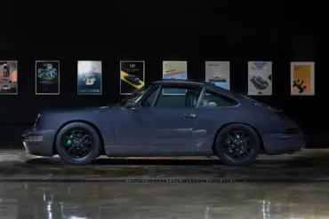 Dunkelgrauer Porsche 911 (964) Carrera 2, Baujahr 1991, mit schwarzen Felgen und grünen Akzenten, seitlich fotografiert in einer Ausstellungshalle