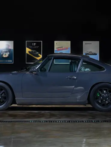 Dunkelgrauer Porsche 911 (964) Carrera 2, Baujahr 1991, mit schwarzen Felgen und grünen Akzenten, seitlich fotografiert in einer Ausstellungshalle