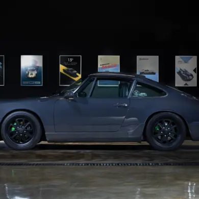 Dunkelgrauer Porsche 911 (964) Carrera 2, Baujahr 1991, mit schwarzen Felgen und grünen Akzenten, seitlich fotografiert in einer Ausstellungshalle