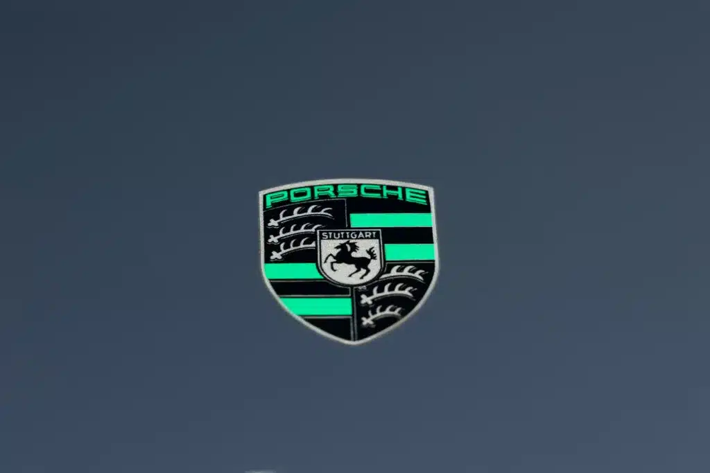 Porsche-Wappen in Schwarz und Türkis auf grauem Hintergrund