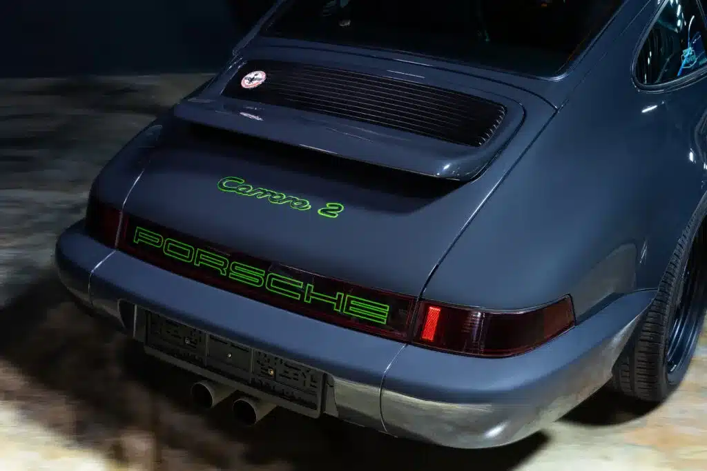 Porsche 911 (964) Carrera 2 in Dunkelgrau mit grünen Carrera 2 und Porsche Schriftzügen am Heck