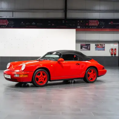 Porsche 911 (964) Carrera Speedster in Indischrot mit schwarzen RS-Schalensitzen und geschlossenem Verdeck, seitliche Ansicht.