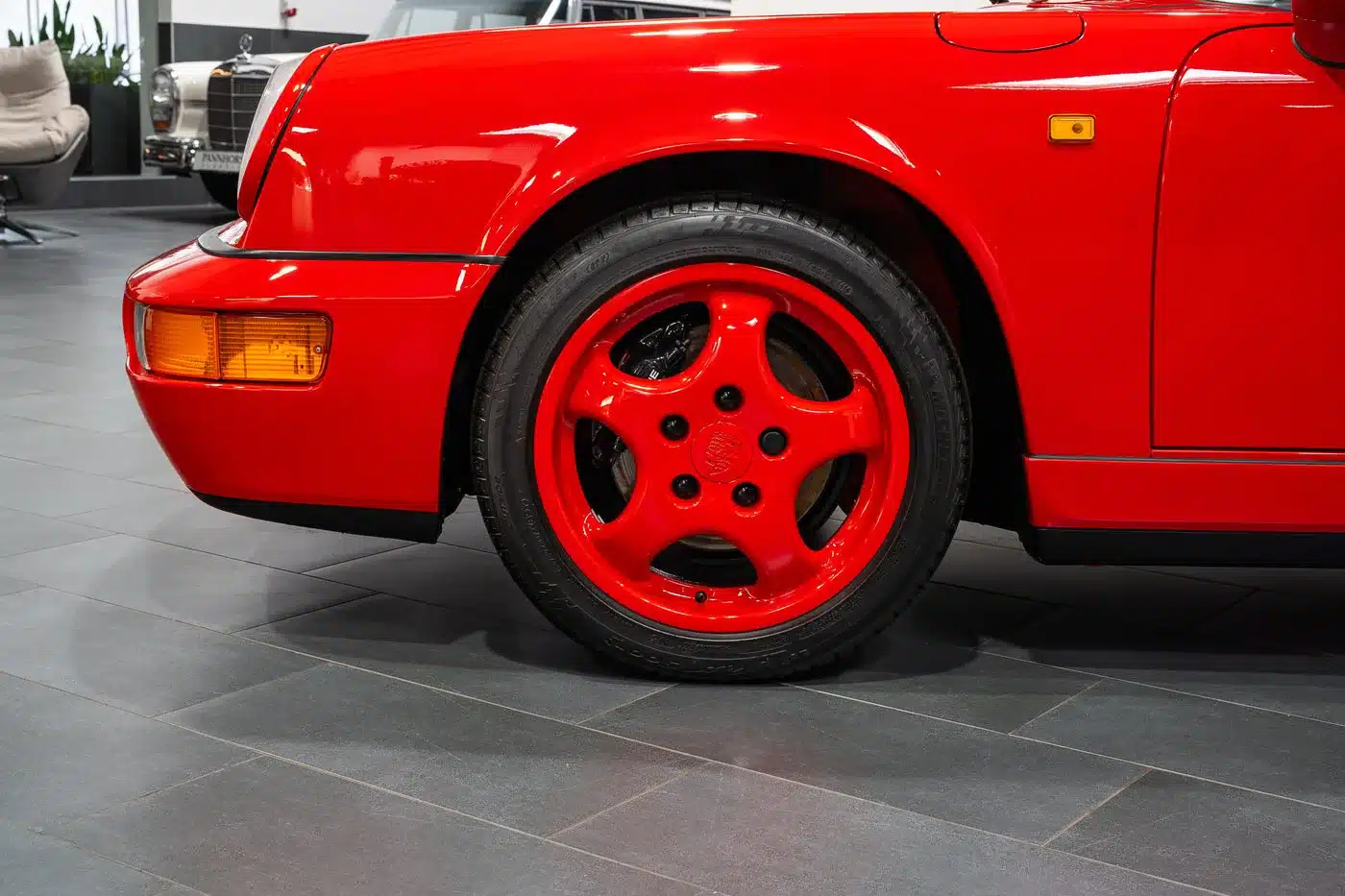 Rotes Vorderrad und Kotflügel eines Porsche 911 (964) Carrera Speedster in Indischrot, Detailaufnahme im Showroom.