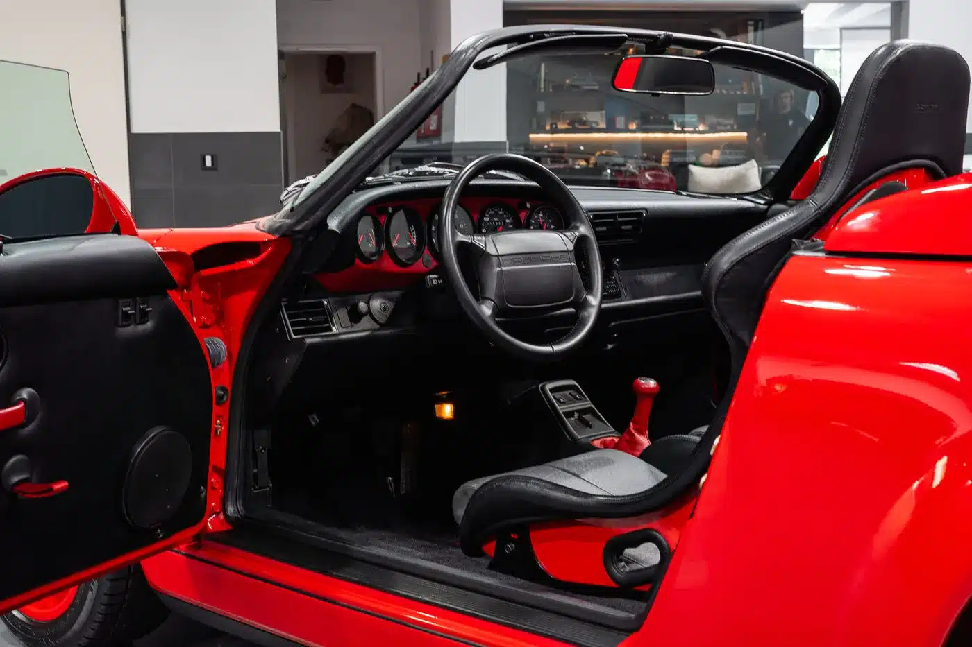 Offener Innenraum eines Porsche 964 Carrera Speedster mit Schalensitzen und rotem Schalthebel