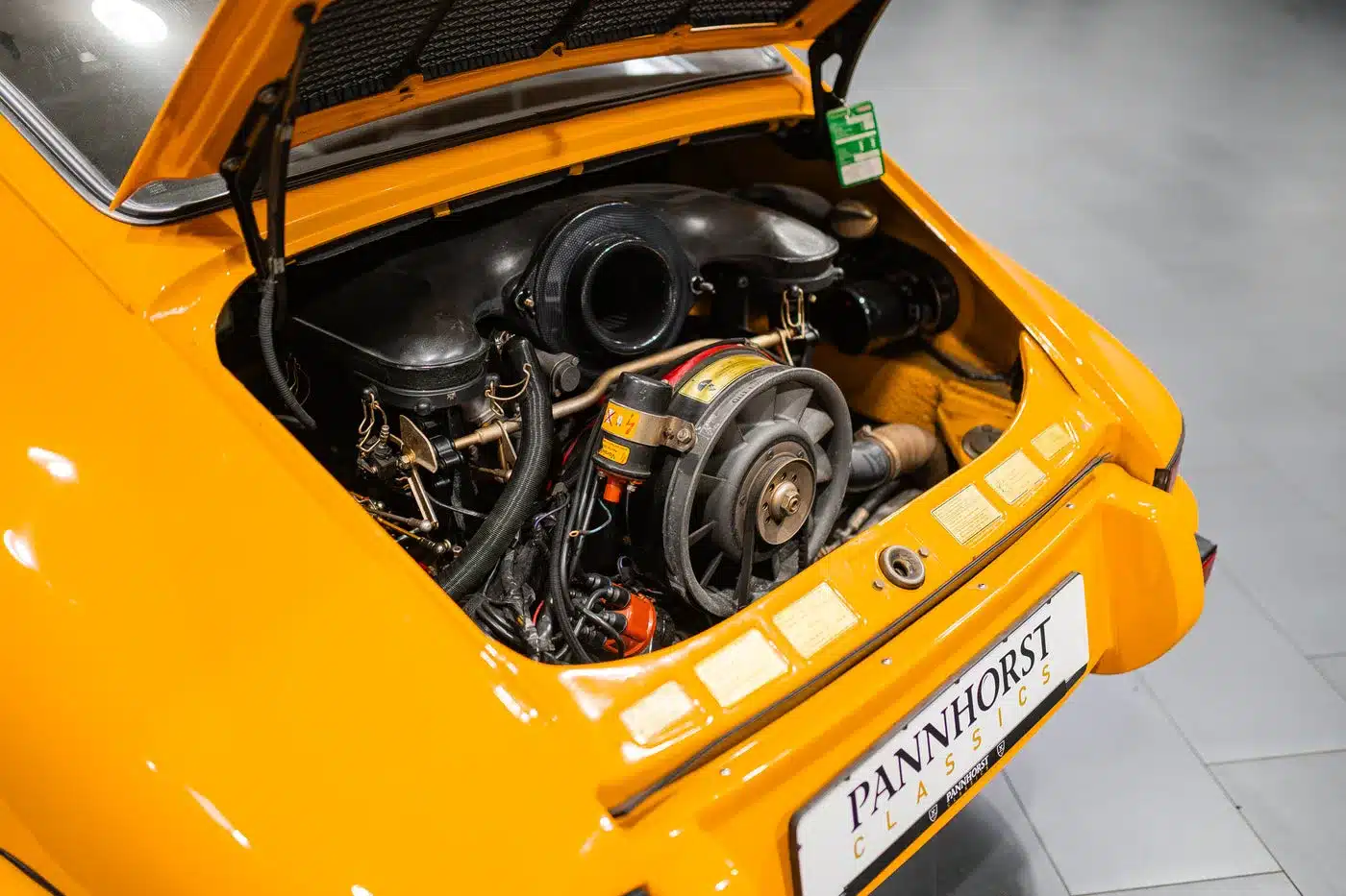 Geöffneter Motorraum eines klassischen gelben Porsche 911 mit sichtbar luftgekühltem Boxermotor