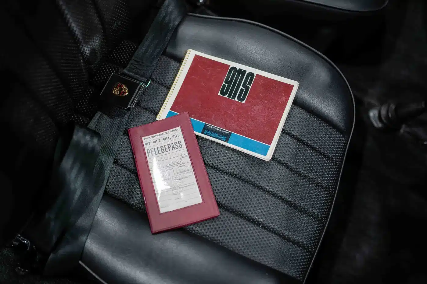 Bedienungsanleitung und Pflegepass eines Porsche 911 S Softwindow Targa von 1967 auf schwarzem Ledersitz