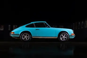 Türkiser Porsche 911T aus dem Jahr 1971, seitliche Ansicht in dunkler Umgebung, Fuchs-Leichtmetallräder sichtbar.