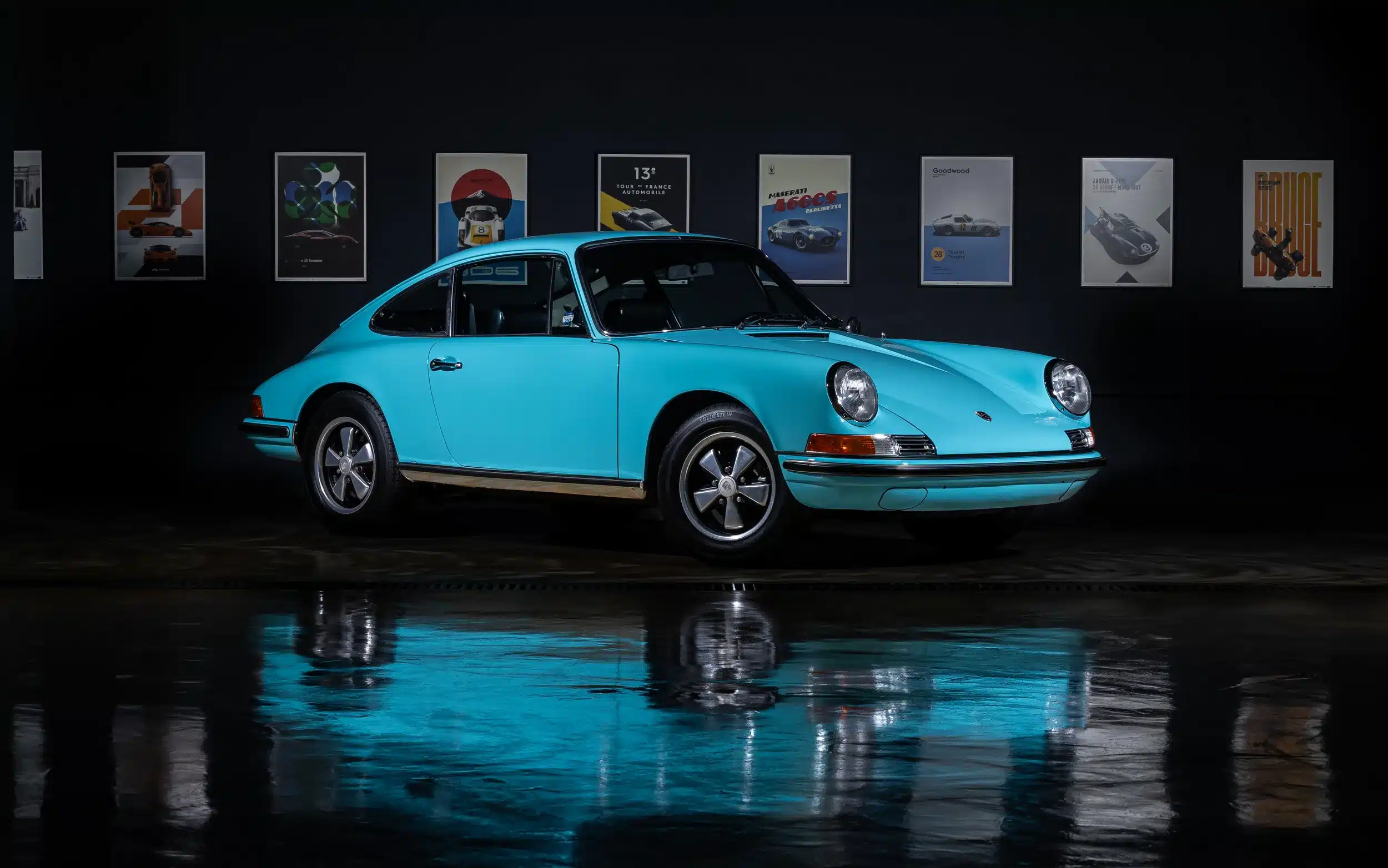 Türkiser Porsche 911T Baujahr 1971 mit Fuchs-Felgen vor dunklem Hintergrund, Seitenansicht.