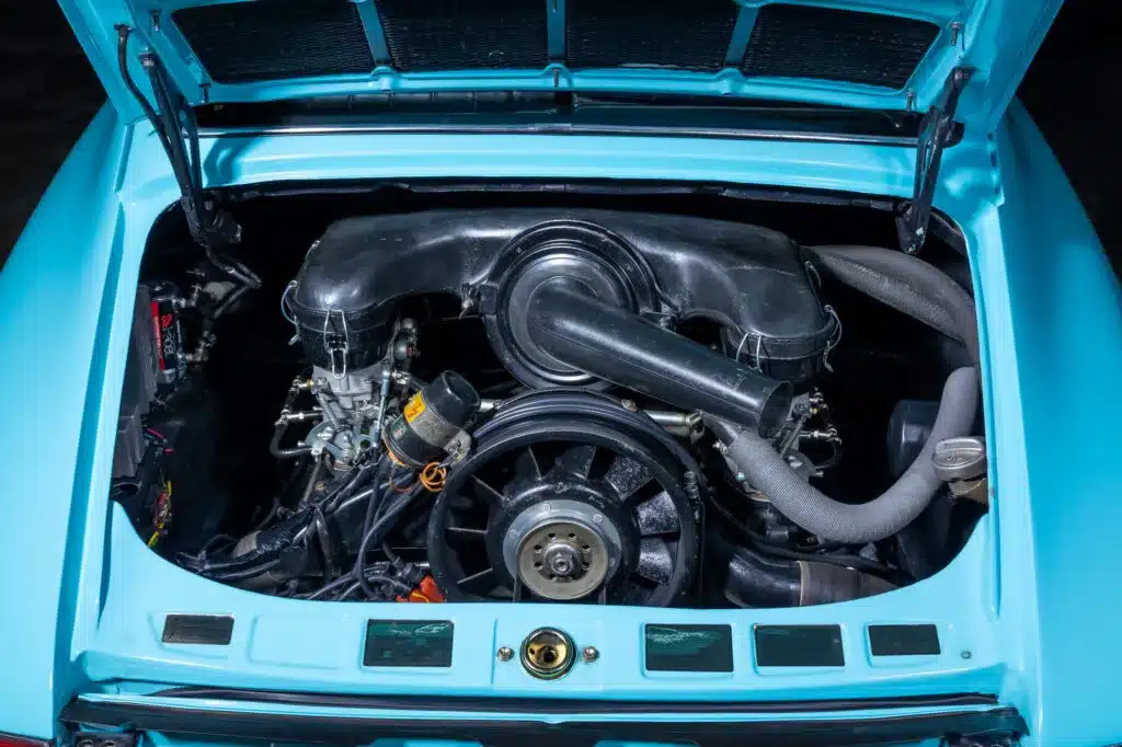 Motorraum eines türkisfarbenen Porsche 911T von 1971 mit offenem Heckdeckel und Boxermotor.