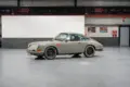 Seitenansicht eines Porsche 912 Coupé von 1966 in Zeltgrau mit schwarzen Felgen, fotografiert in einer modernen Halle.