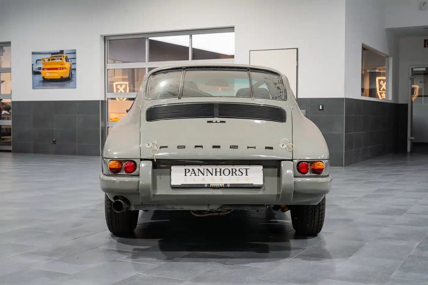 Heckansicht eines Porsche 912 Coupé Baujahr 1966 in Zeltgrau, fotografiert in einer modernen Fahrzeughalle.