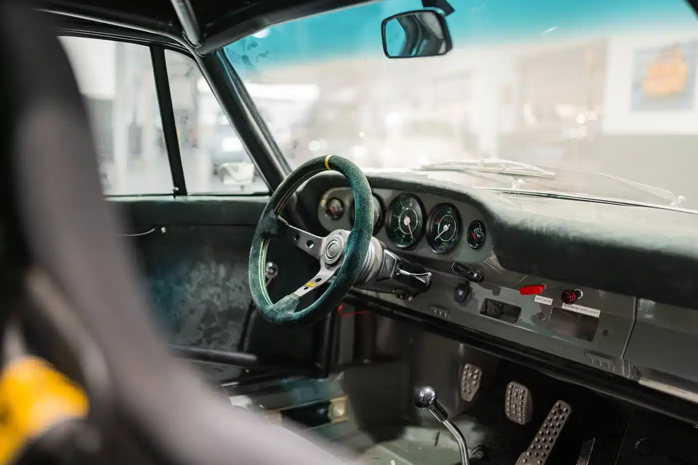 Innenraumansicht eines restaurierten Porsche 912 Coupé mit Rennsportausstattung, Schalensitz und sportlichem Lenkrad.