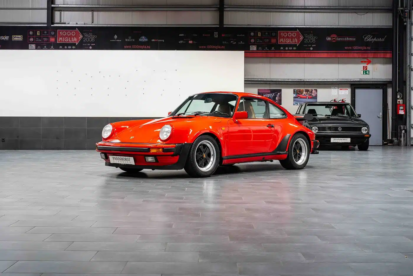 Roter Porsche 930 Turbo aus den 1970er/80er Jahren, fotografiert in einer modernen Fahrzeughalle.