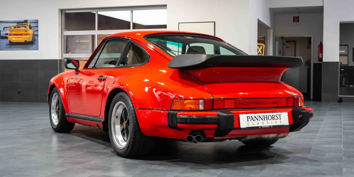 Roter Porsche 930 Turbo von hinten, ausgestellt in einem modernen Showroom