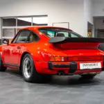 Roter Porsche 930 Turbo von hinten, ausgestellt in einem modernen Showroom